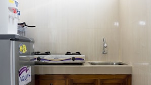 Una cocina compacta con refrigerador, estufa a gas, lavamanos y armarios de madera.