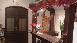 A room with a checkered floor, a wooden door, and a decorative altar with flowers and a statue.