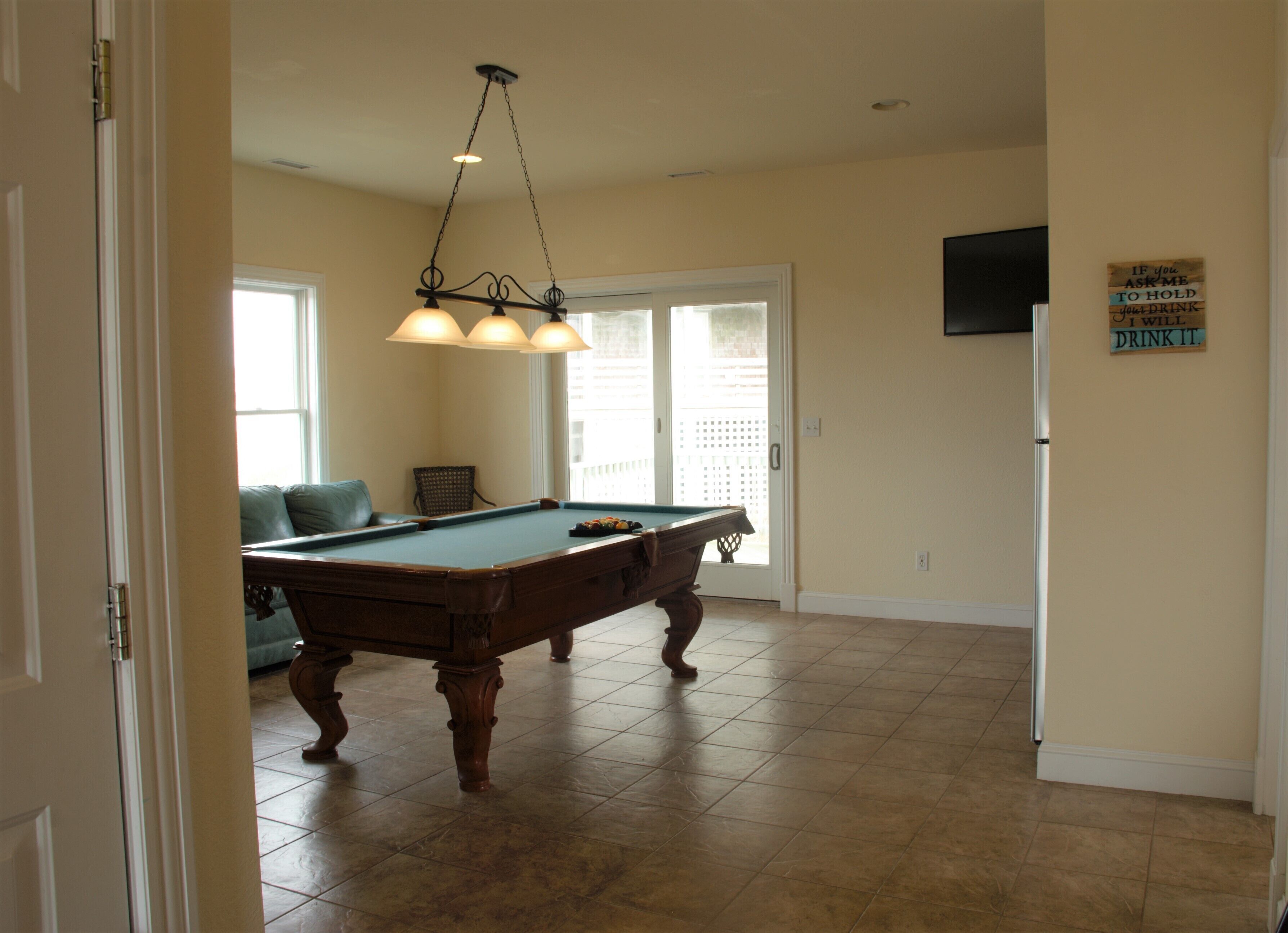 A pool table in a room with a door, a window, and a wall-mounted sign.