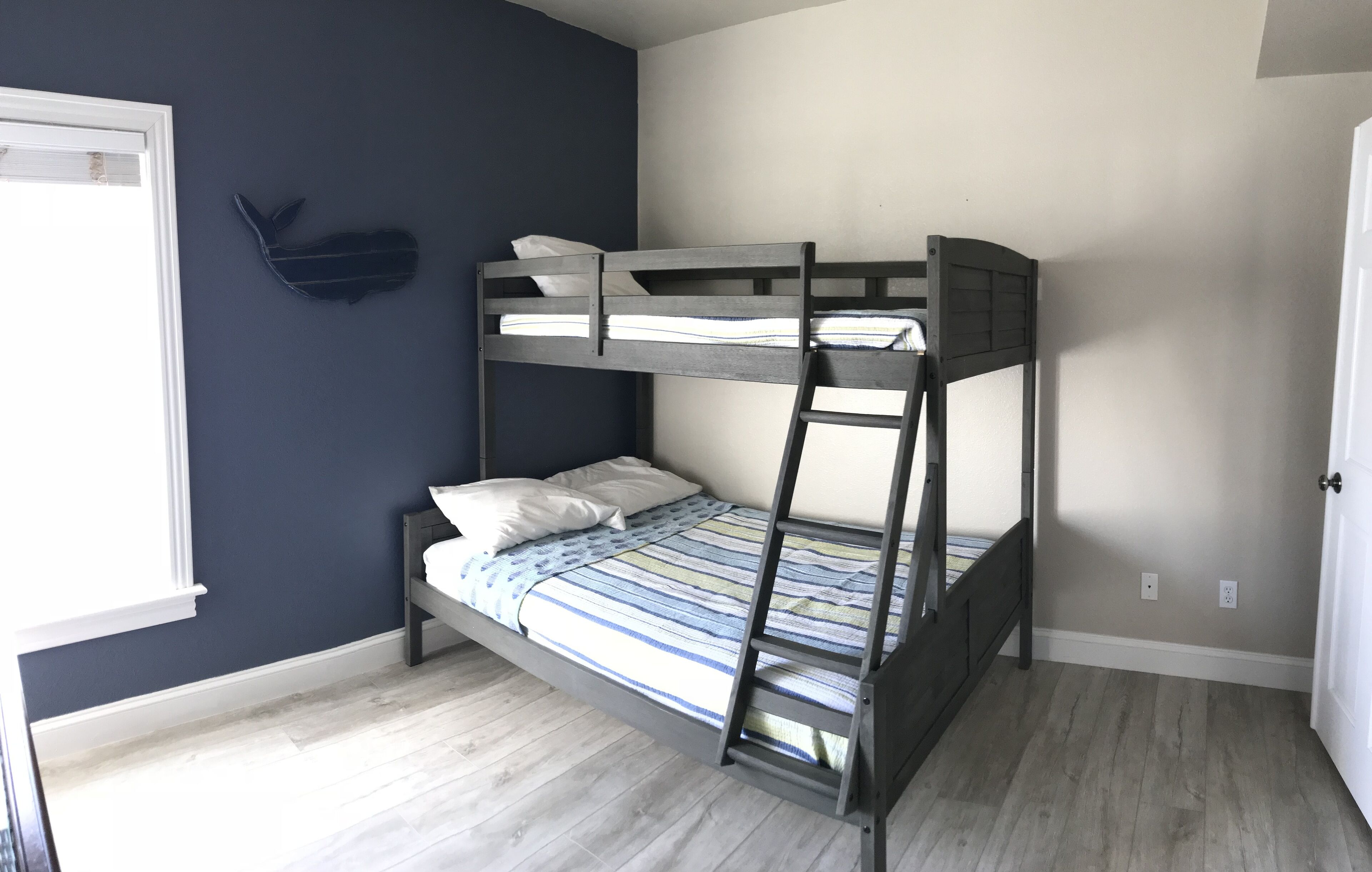 Un lit superposé avec une échelle, une fenêtre et un élément décoratif fixé au mur.