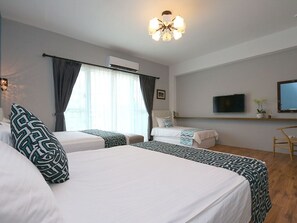 Una habitación de hotel con dos camas, televisión, escritorio y silla.