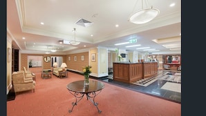 A spacious lobby with a reception desk, seating area, and a patterned carpet. - S&P Apartments - Central Station (Brisbane)