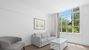 A room with a grey sofa, a white coffee table, and a framed picture on the wall. - S&P Apartments - Central Station (Brisbane)