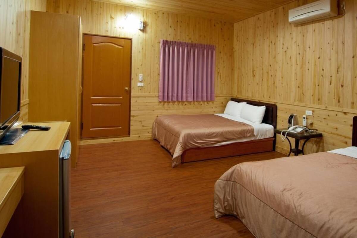 Ein Zimmer mit zwei Betten, einem Schreibtisch und einem Fernseher sowie einer Klimaanlage.