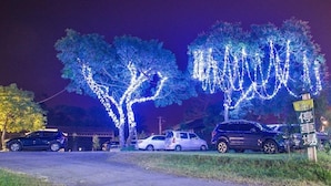 A parking area with trees decorated with lights, a sign indicating a parking area, and several parked cars. - CDR Hotspring Resort (Kaohsiung)