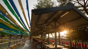 An outdoor seating area with tables and chairs, a covered section, and a view of the sunset over a body of water. - CDR Hotspring Resort (Kaohsiung)