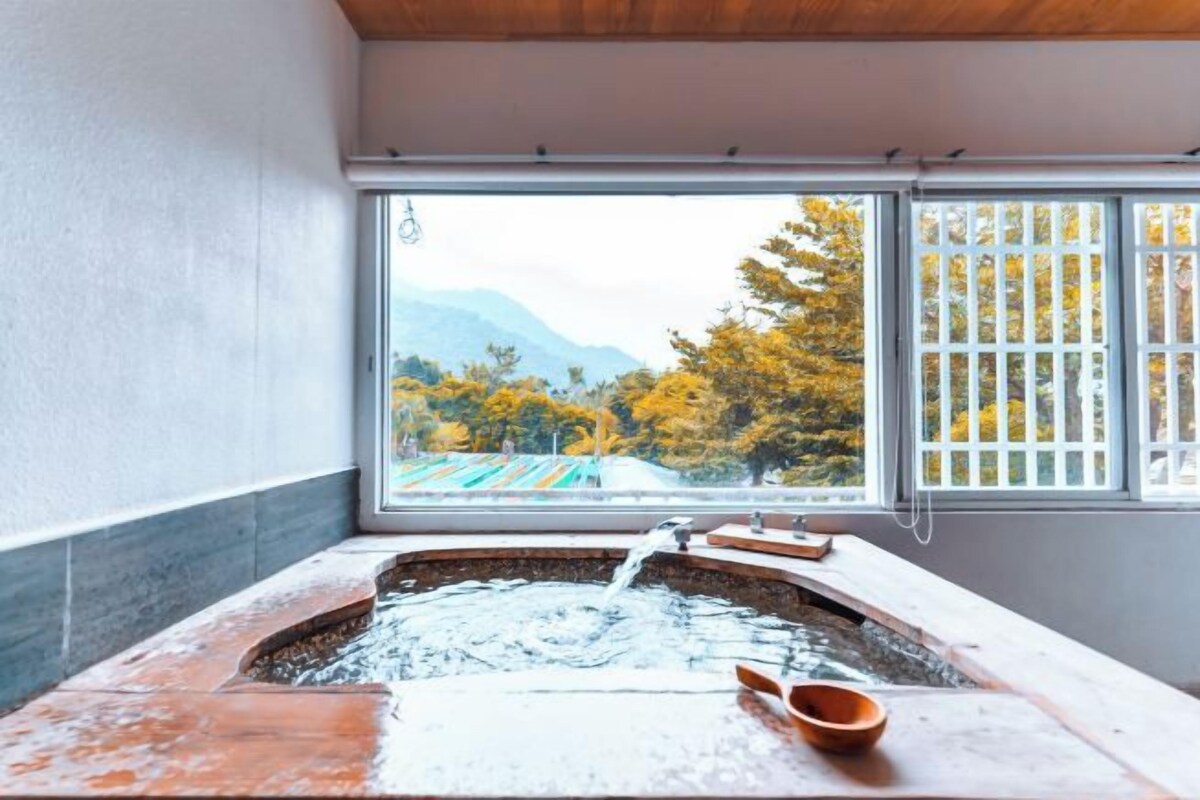 A hot tub with a view of autumn trees and mountains through a window.