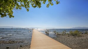 A wooden boardwalk leading to a rocky shoreline with boats in the water. - Fantastic Forest Setting Rocky Ridge #120 (Tahoe City)