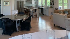 Un'ampia cucina con elettrodomestici moderni, un'area pranzo con un tavolo rotondo e un soggiorno con divano.