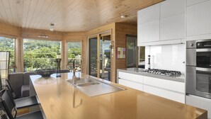 Una cocina moderna con techo de madera, electrodomésticos de acero inoxidable y una isla grande con fregadero.