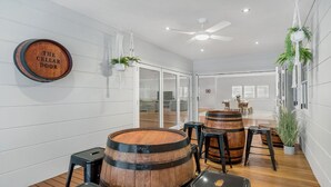 Ein modernes Interieur mit Holzfässern, einem Deckenventilator und einem Schild mit der Aufschrift 'The Cellar Door'.