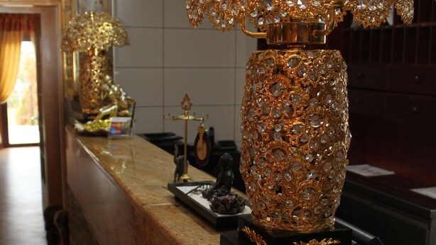 A reception desk with a decorative lamp, a clock, and a statue on the counter. - Hotel Langenthal (Langenthal)