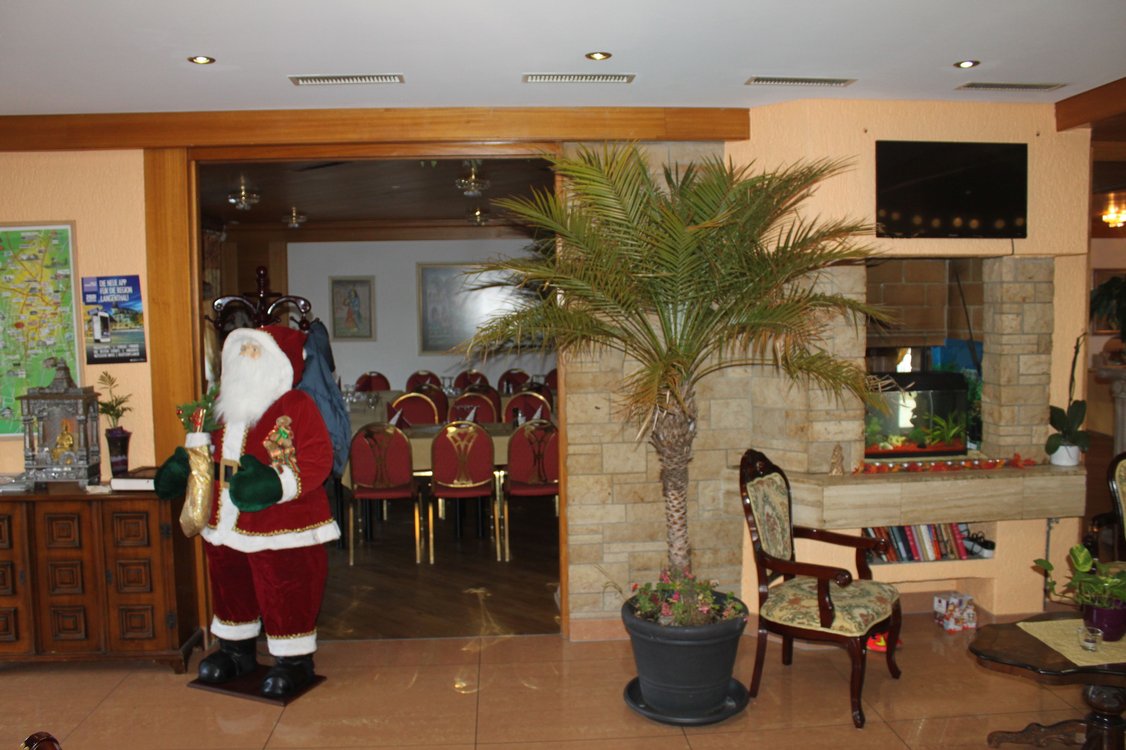 A lobby with a large Santa Claus statue, a palm tree, and a fireplace.