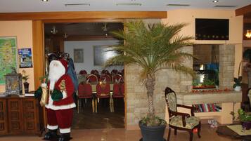 A lobby with a large Santa Claus statue, a palm tree, and a fireplace.