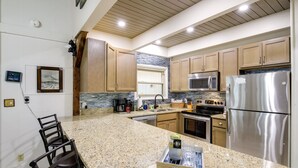 Eine moderne Küche mit Granit Arbeitsplatten, Edelstahlgeräten und Holzschränken.