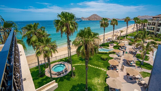 A resort with a pool, palm trees, and a beach view. - Beachfront 4th Floor with Stunning Views to Lands End, Medano Beach and Cabo San Lucas Bay (Cabo San Lucas)