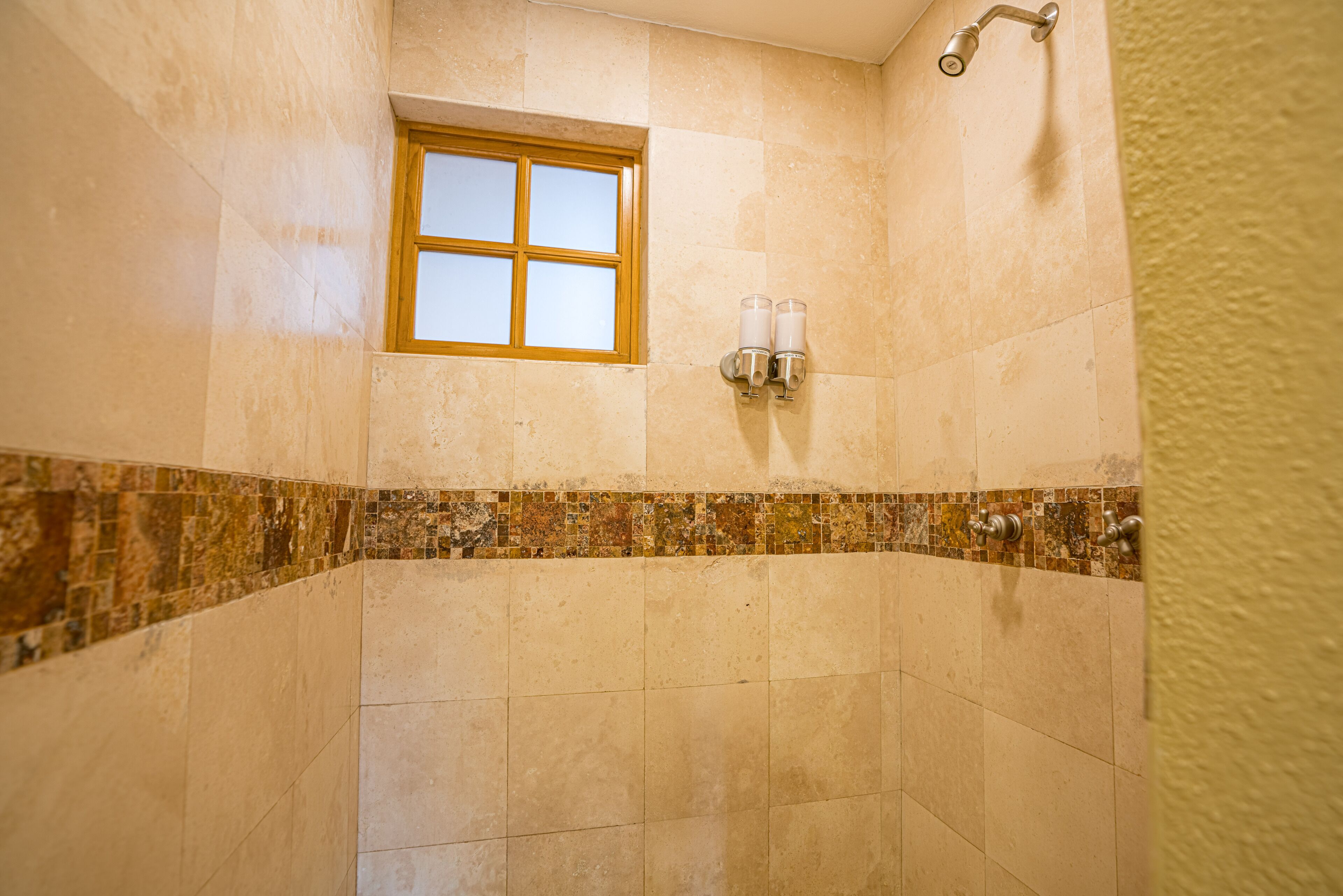 Un baño con ventana, paredes de azulejos y zona de ducha.