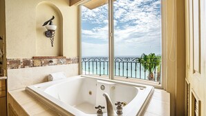 A bathroom with a large bathtub, a view of the ocean through a balcony, and a decorative wall fixture. - Beachfront 4th Floor with Stunning Views to Lands End, Medano Beach and Cabo San Lucas Bay (Cabo San Lucas)