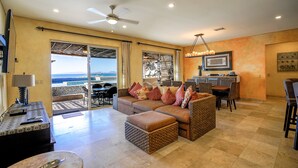 A spacious living area with a large sofa, a dining table, and a bar area. - BEACHFRONT, PRIVATE POOL, GOLF, Concierge, Daily Maid and Chef-Meal Services at Paraiso del Mar (La Paz)