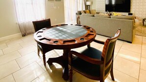 A living room with a round wooden table, two chairs, a sofa, a TV, and a patterned wall. - 6BR Solterra Pool Home | Spa, Game Room, BBQ, Themed Rooms & 3 Kings (Davenport)