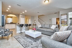 Ein modernes Wohnzimmer mit einem grauen Sofa, einem weißen Couchtisch und einem gemusterten Teppich.