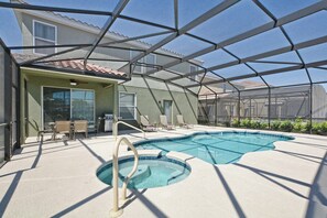 Ein überdachter Pool mit Terrassenbereich, Stühlen und einem Haus im Hintergrund.