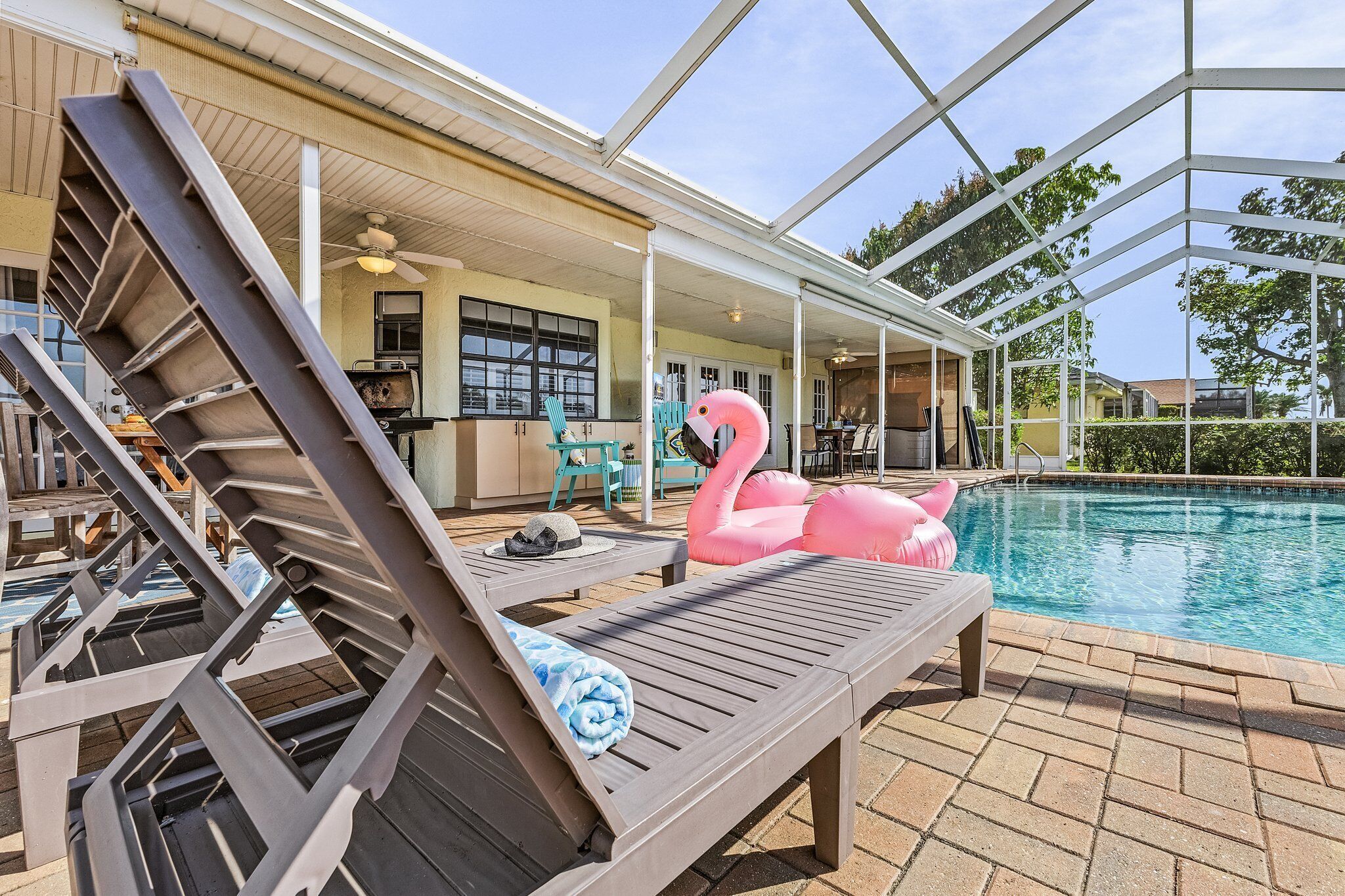 Ein Poolbereich mit Liegestühlen, einem Flamingo-Schwimmpfad und einer überdachten Terrasse.