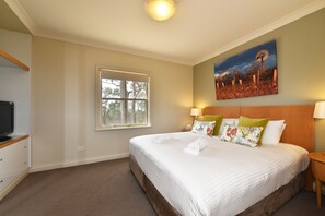 Ein Hotelzimmer mit einem großen Bett, einem Fernseher, einem Fenster und einem Bild an der Wand.