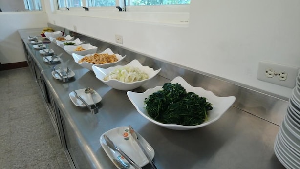 Ein Buffet mit verschiedenen Speisen in weißen Schalen, darunter Salate und weitere Gerichte.