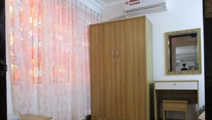 A room with a wooden wardrobe, a small desk, a mirror, and a curtain. - City Backpackers Hostel (Ho Chi Minh City)