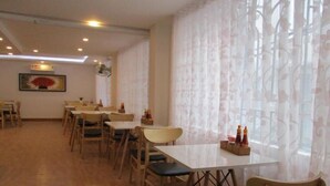 A dining area with tables and chairs, a ceiling fan, and a window with curtains. - City Backpackers Hostel (Ho Chi Minh City)