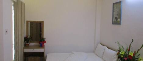 Ein Schlafzimmer mit Bett, Nachttisch, Schreibtisch, Stuhl und Spiegel.