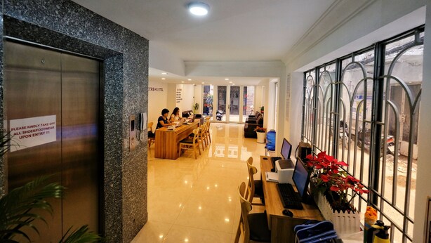 A hotel lobby with a reception desk, seating area, and an elevator. - City Backpackers Hostel (Ho Chi Minh City)