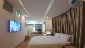 A hotel room with a large bed, a TV on the wall, a desk with a chair, and a window with curtains. - City Backpackers Hostel (Ho Chi Minh City)