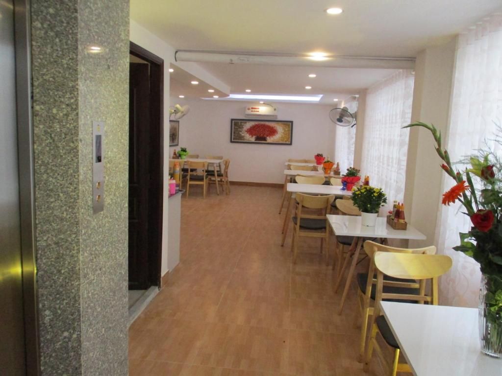 Una zona de menjador amb taules i cadires, un quadre a la paret i una porta que condueix a una altra habitació.