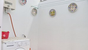Une buanderie équipée d’un lave-linge, d’un panier rouge et de trois assiettes décoratives accrochées au mur.