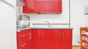 Une cuisine de taille réduite avec des placards rouges, un four à micro-ondes, un grille-pain et un évier.