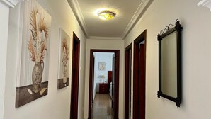 A hallway with a ceiling light, framed artwork on the walls, and a mirror.