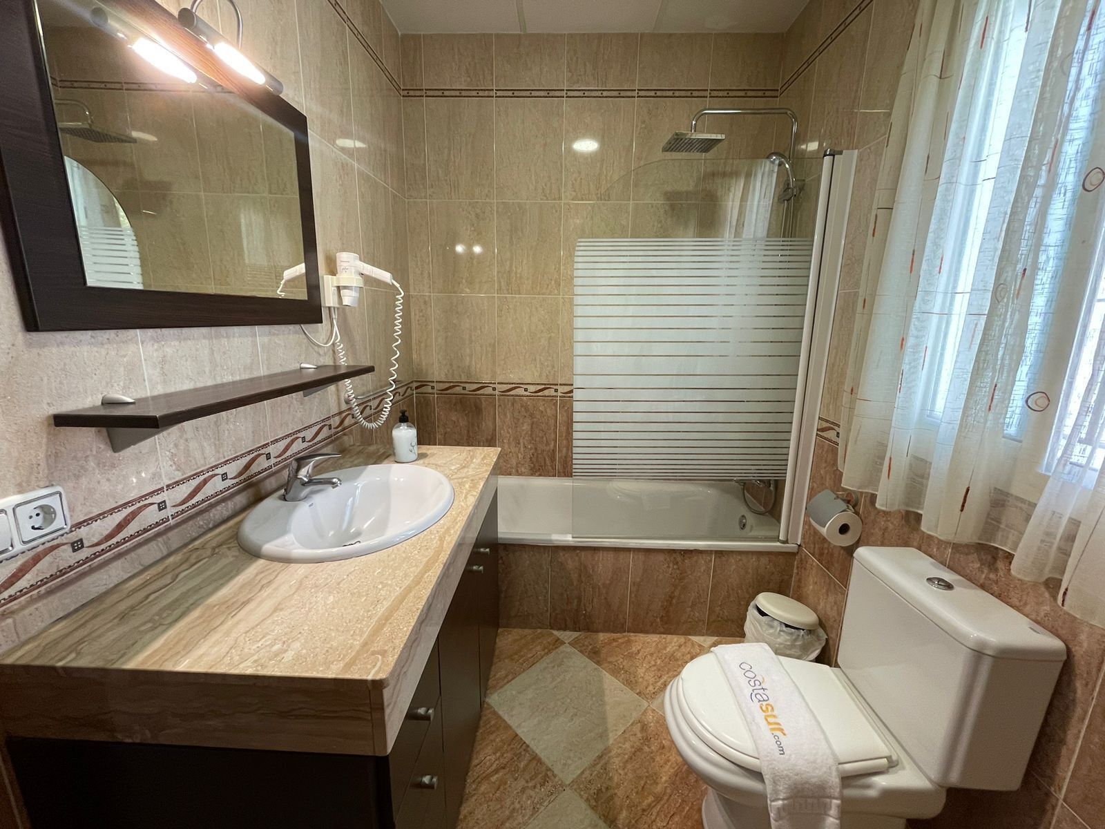 Un baño con lavamanos, espejo, inodoro y ducha.