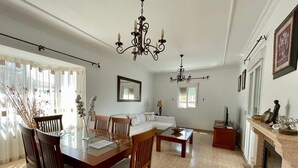 A spacious living room with a dining area, a fireplace, and a large window.