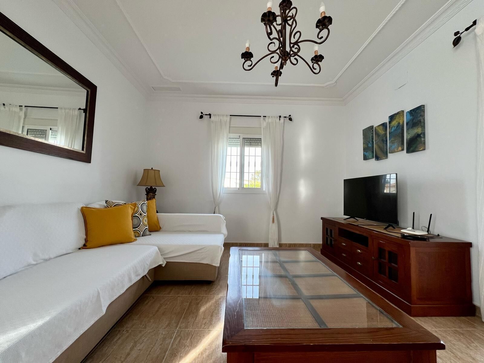 A well-lit living room with a sofa, a coffee table, a TV, and artwork on the wall.