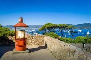 A coastal view with a stone wall, a red lantern, and a clear blue sky.