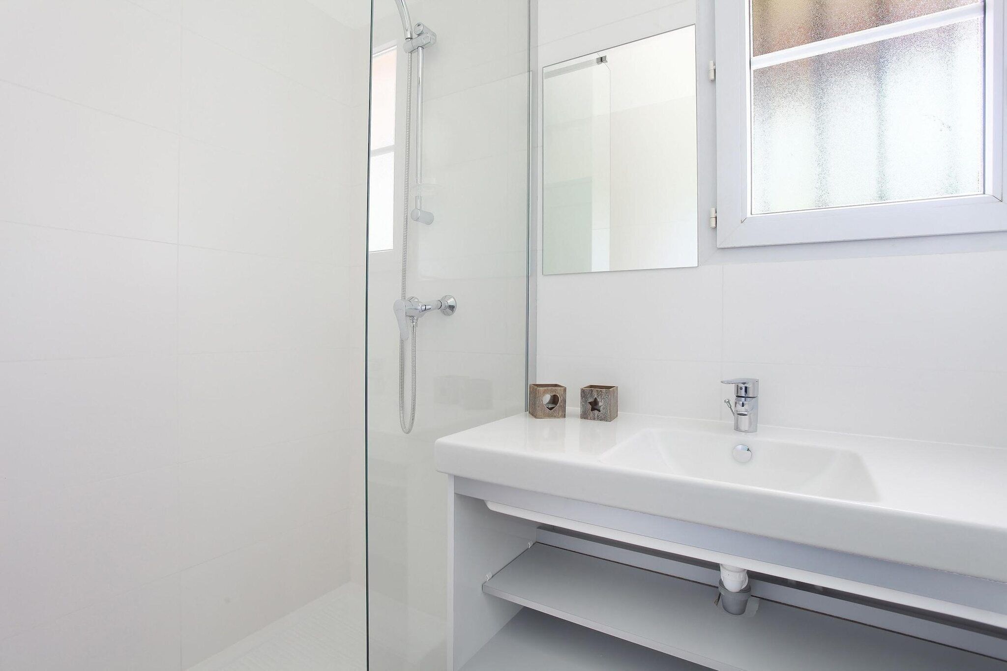 A bathroom with a glass shower enclosure, a white sink, and a mirror above it.