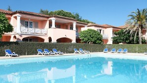 A swimming pool with lounge chairs and a building with balconies. - Apartment in Grimaud with Pools (GRIMAUD)