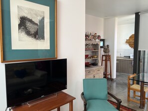 A living room with a flat-screen TV, a framed abstract painting, and a teal armchair. - Department in the Heart of Oaxaca (Oaxaca)