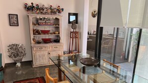 A dining area with a glass table, wooden chairs, a patterned rug, and a decorative cabinet with various items. - Department in the Heart of Oaxaca (Oaxaca)
