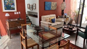 A living room with a glass-top dining table, leather sofa, and a staircase. - Department in the Heart of Oaxaca (Oaxaca)
