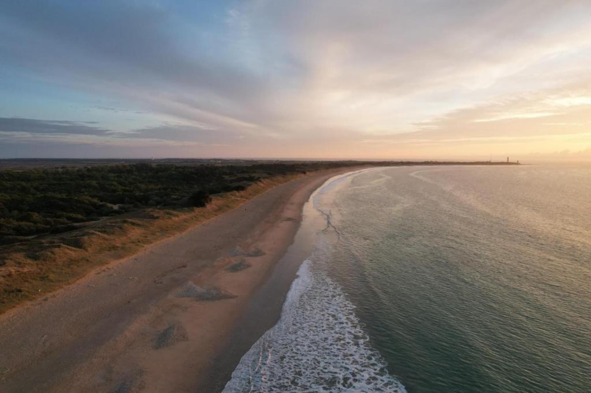 Un paysage côtier avec une plage de sable et une mer calme.