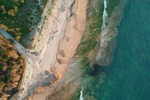 A coastal landscape with a sandy beach, rocky cliffs, and a clear view of the ocean. - Nice apartment on the island of Ile de Ré (RIVEDOUX PLAGE)