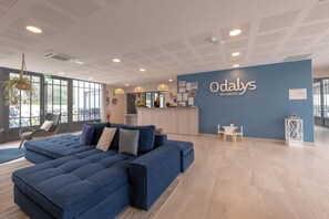 A modern hotel lobby with a large blue sofa, a reception desk, and a sign reading 'Odalys Vacances'. - Nice apartment on the island of Ile de Ré (RIVEDOUX PLAGE)